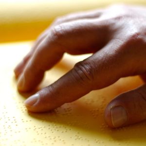 Zu sehen ist die Hand von Reiner Unglaub, mit der er gerade einen Punktschrifttext liest.